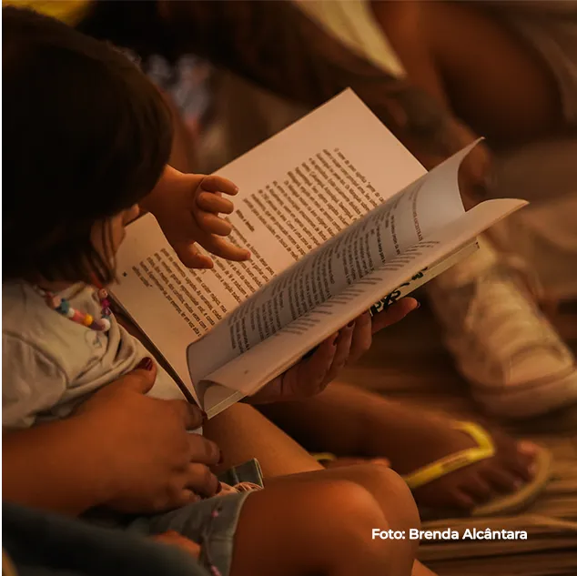Criança lê um livro sentada ao sol