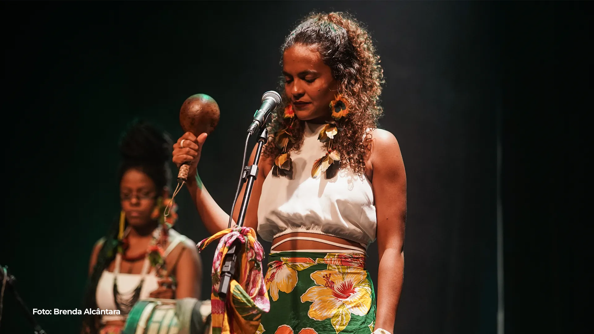 Cantoras se apresentam ao microfone diante do público